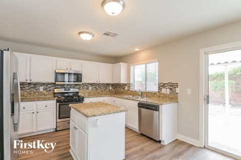 A kitchen with white cabinets and a granite countertop.