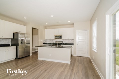 A kitchen with white cabinets and a stainless steel refrigerator.