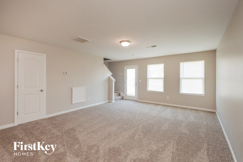 an empty living room with a white door and window