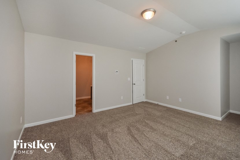 an empty living room with carpet and a door to a hallway