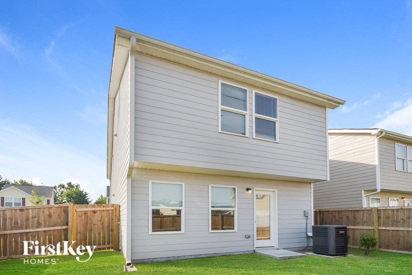 the exterior of a white house with a yard and a fence