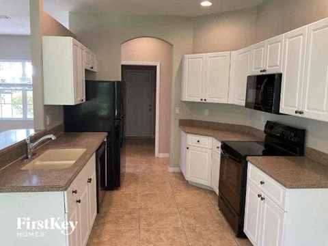 a kitchen with white cabinets and a black refrigerator
