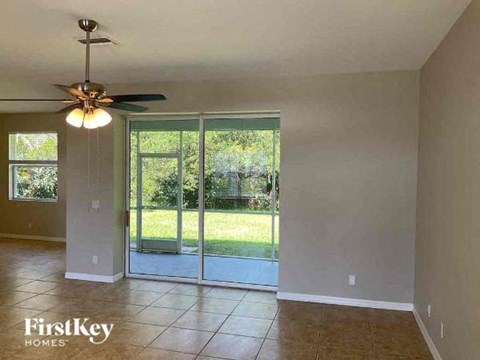 an empty living room with a ceiling fan and a sliding glass door