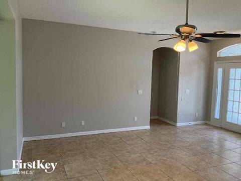 a empty living room with a ceiling fan and tiled floor