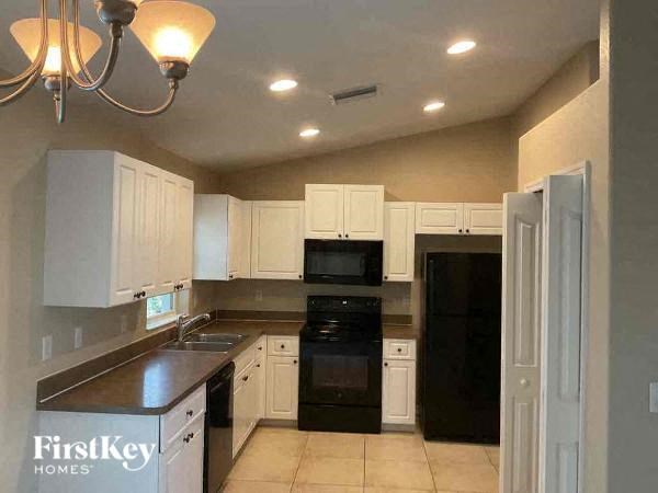 a kitchen with white cabinets and black appliances