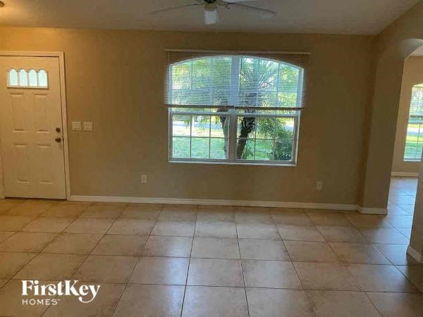 an empty living room with a large window and tiled floor