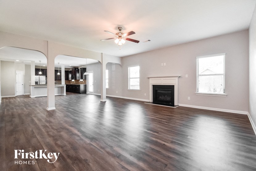 an empty living room with a ceiling fan and a fireplace