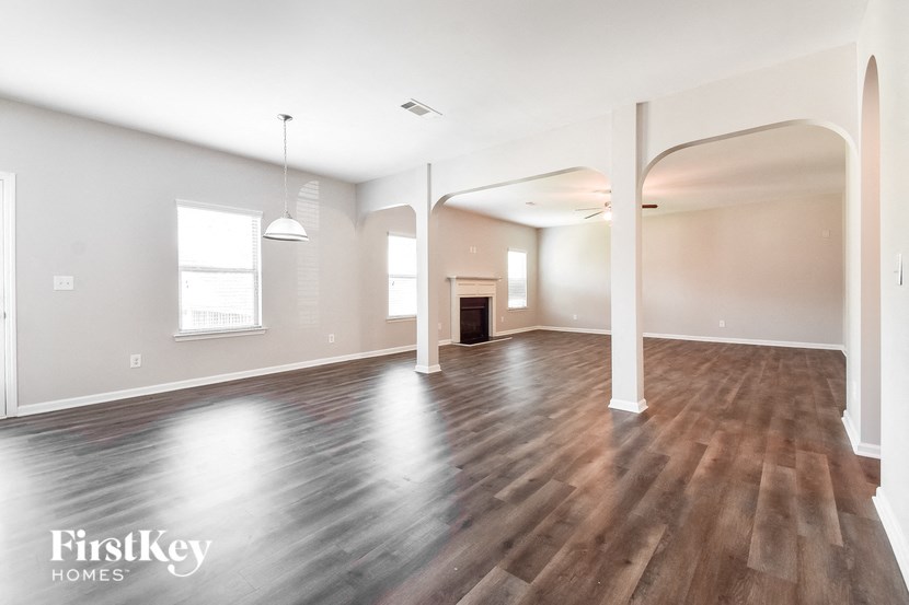 the living room and dining room with wood floors and white walls