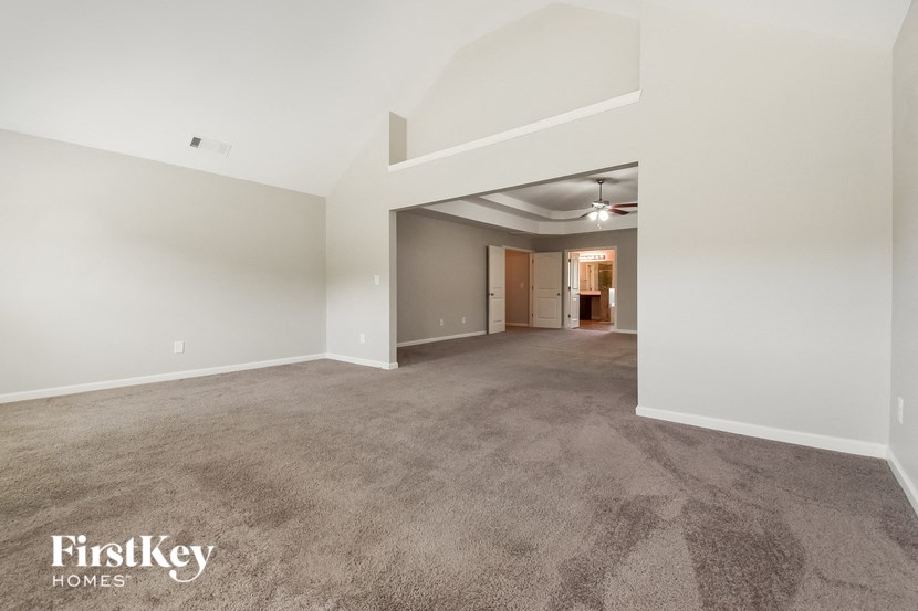 a spacious living room with carpet and white walls