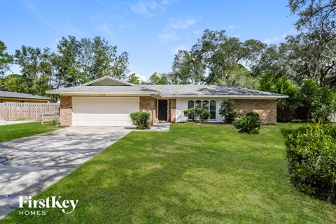 a small brick house with a lawn and a driveway