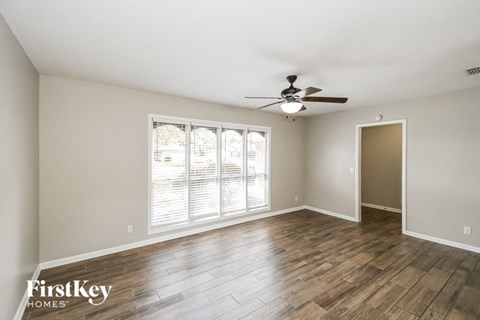 an empty living room with a ceiling fan and a large window