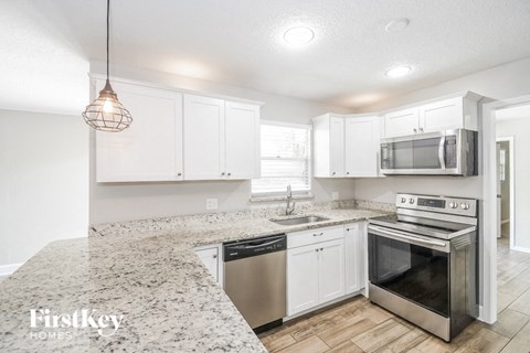 a kitchen with white cabinets and a marble counter top