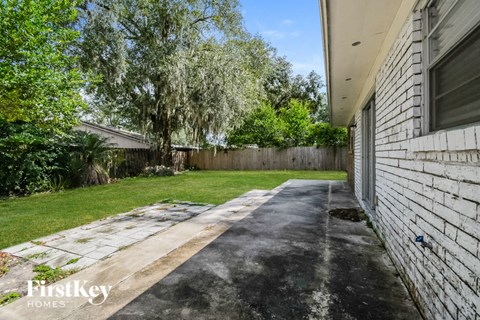 a backyard with a white brick wall and a lawn and trees