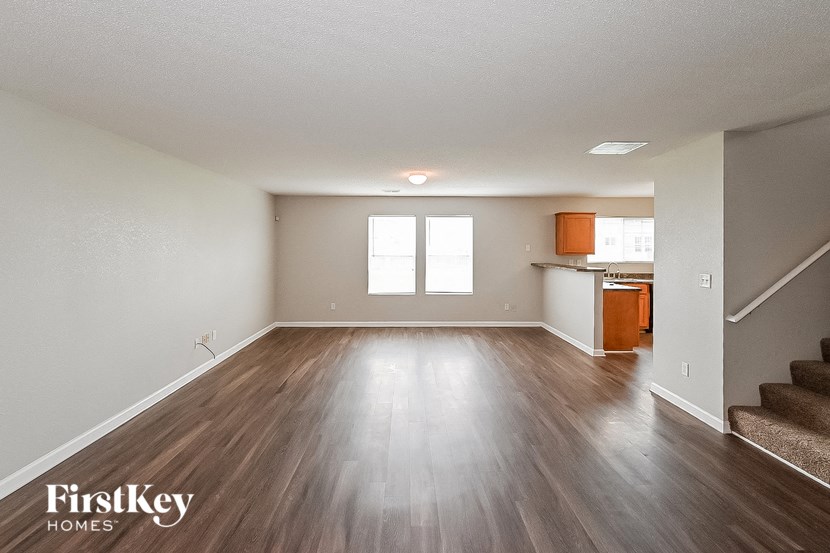 an empty living room and kitchen with wood floors