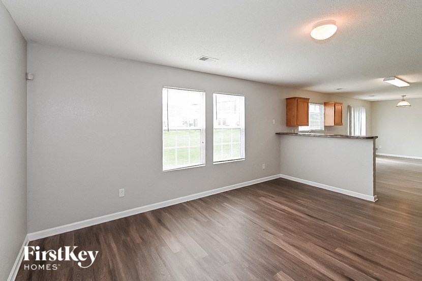 an empty living room and kitchen with wood flooring