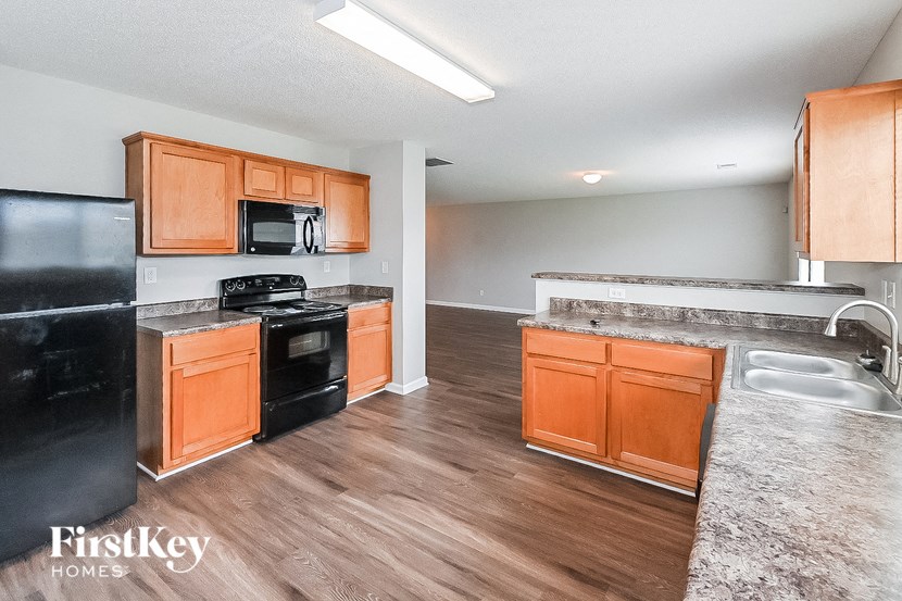 a kitchen with wood flooring and wooden cabinets and black appliances