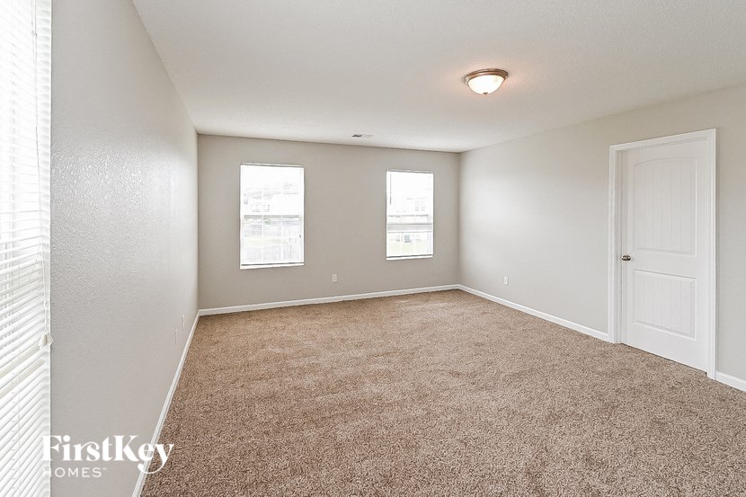 an empty room with a door and two windows