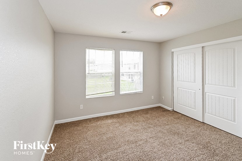 an empty bedroom with two windows and a door