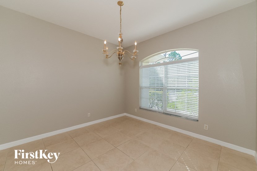 an empty dining room with a large window and a chandelier