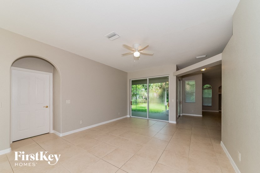a empty living room with a ceiling fan and a door to a yard