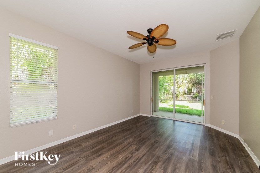an empty living room with a ceiling fan and a sliding glass door