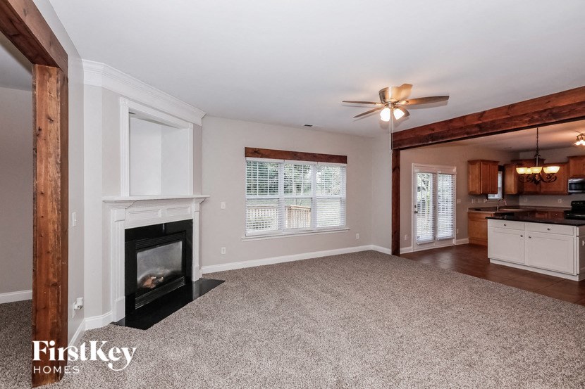 an empty living room with a fireplace and a kitchen