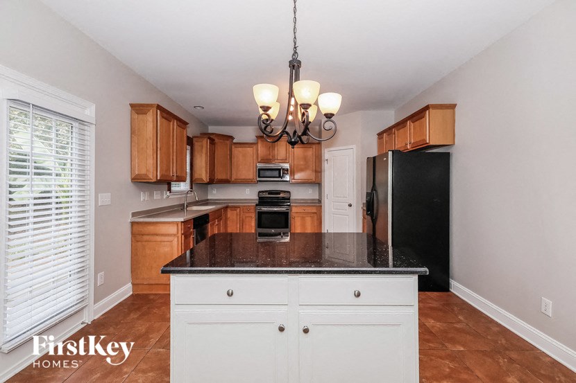 a kitchen with wooden cabinets and black counter tops and a black refrigerator