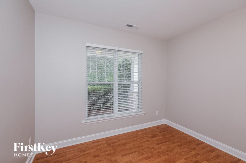 a bedroom with a large window and wood floors