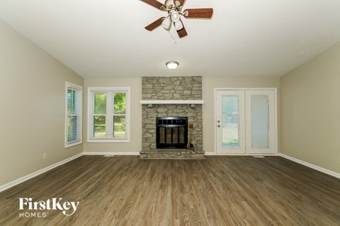 A spacious room with a fireplace and a ceiling fan.