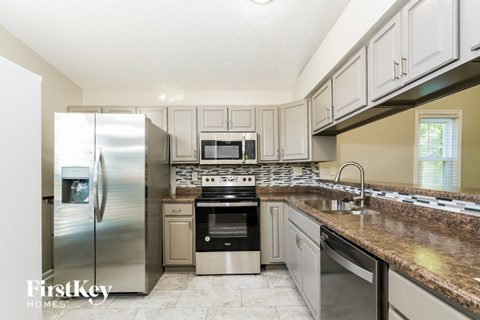 A kitchen with a stainless steel refrigerator and a granite countertop.