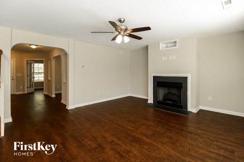 A spacious living room with a fireplace and a ceiling fan.