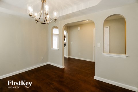 A well-lit room with a chandelier and arched doorways.