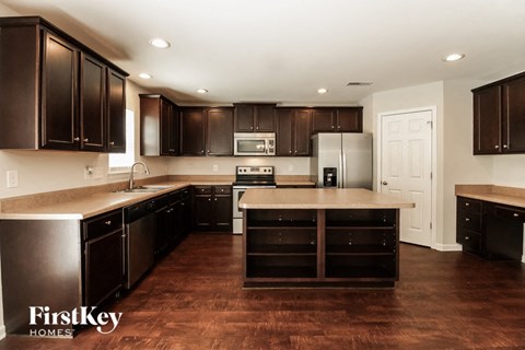 A kitchen with dark brown cabinets and a wooden floor.