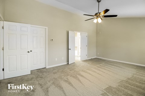 A spacious room with a ceiling fan and carpeted floor.