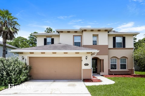 a beige house with a garage door and a palm tree