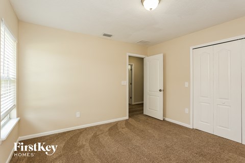a bedroom with a carpeted floor and a door to a closet