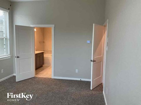 an empty bedroom with a door open to a bathroom