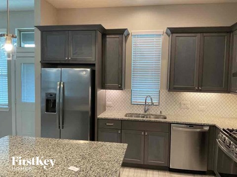 a kitchen with black cabinets and a stainless steel refrigerator
