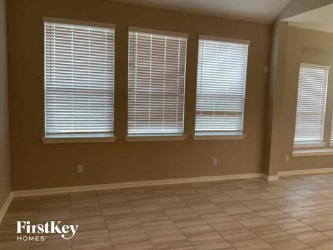 a living room with three windows and a tiled floor