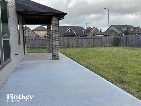 a backyard with a concrete walkway and a house with a fence