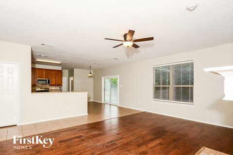A spacious living room with a wood floor and a ceiling fan.