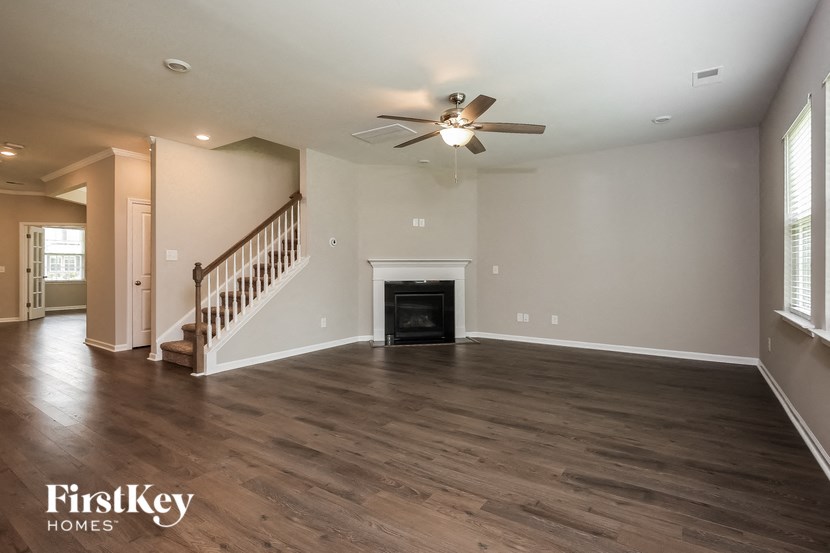A spacious living room with a fireplace and a staircase.