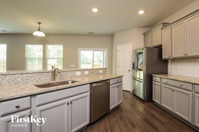 A kitchen with a sink, refrigerator, and cabinets.