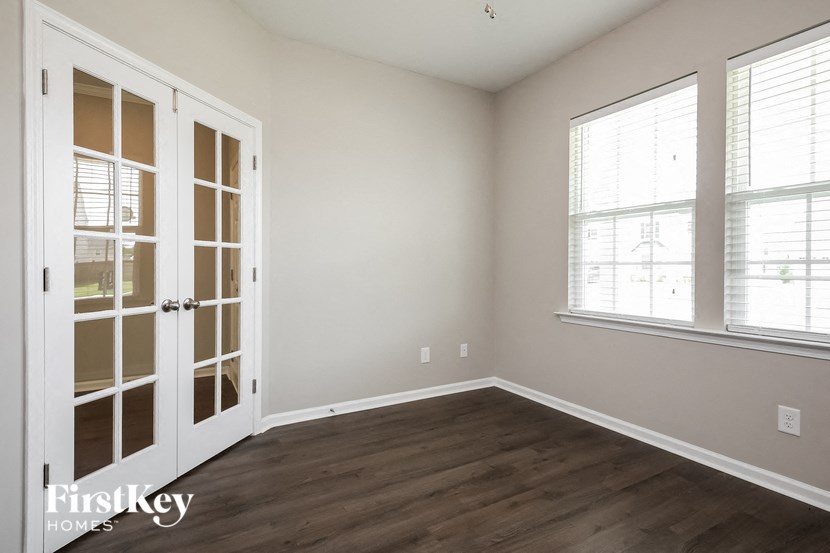 A room with a white door and a window with blinds.