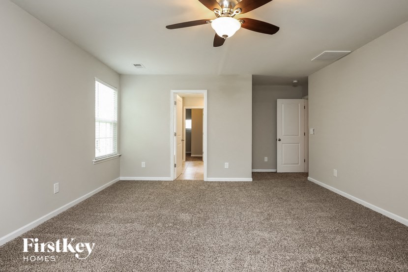 A spacious room with a ceiling fan and carpeted floor.