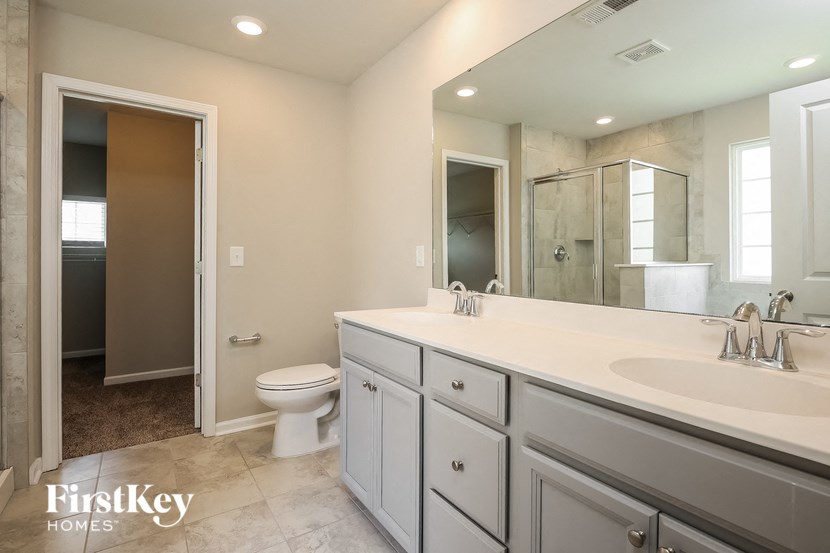 A bathroom with a toilet, sink, and mirror.