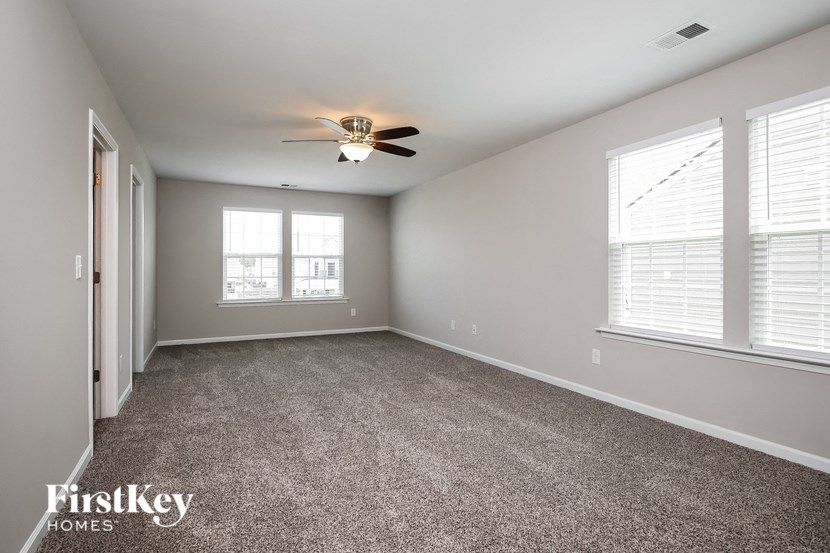 A spacious room with a ceiling fan and carpeted floor.