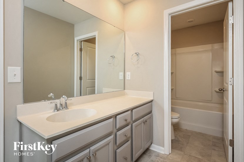 A bathroom with a sink, mirror, and bathtub.