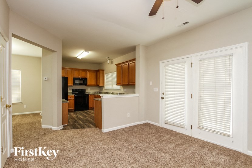 the living room and kitchen of an empty house with white shutters and a door