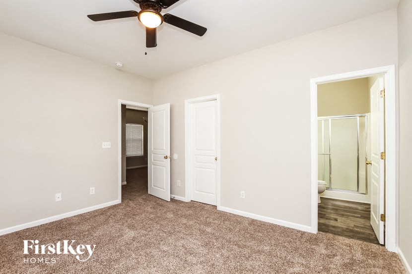 a bedroom with a ceiling fan and a door to a bathroom